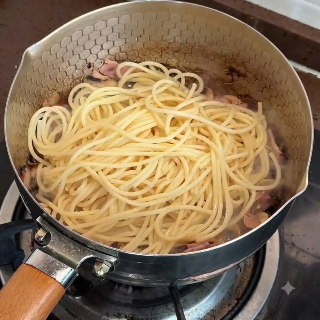 Pasta in padella pronta per essere mescolata con la crema di tartufo e tuorlo duovo.