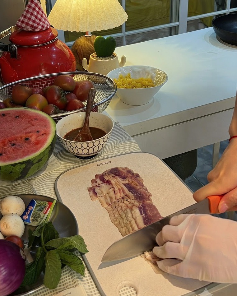 Una cipolla rossa tagliata a metà su un tagliere vicino a un piatto di funghi e menta fresca.