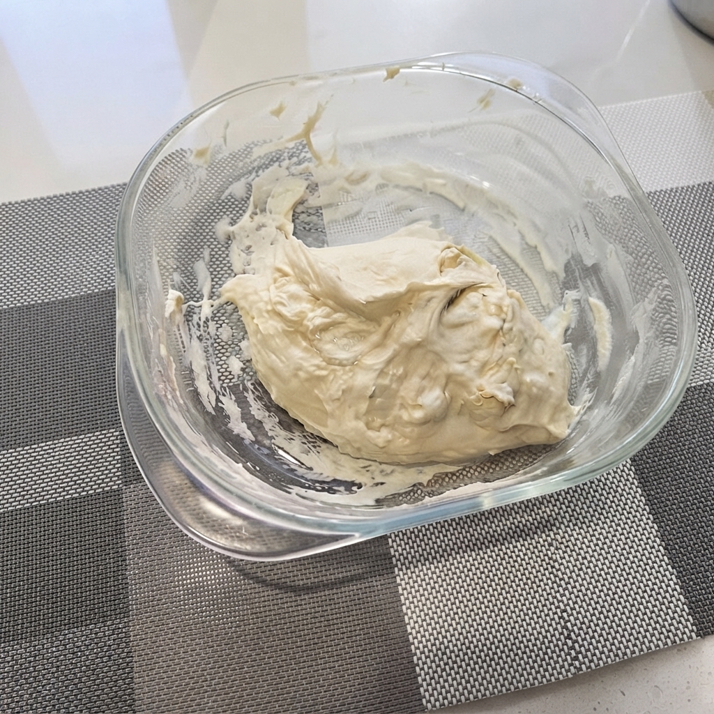 Impasto grezzo per pizza raccolto in una ciotola di vetro trasparente.