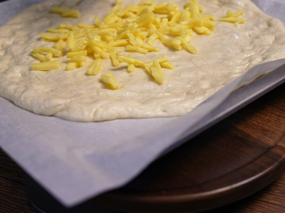 Funghi affettati saltati posizionati sopra lo strato di formaggio sulla pasta della pizza.