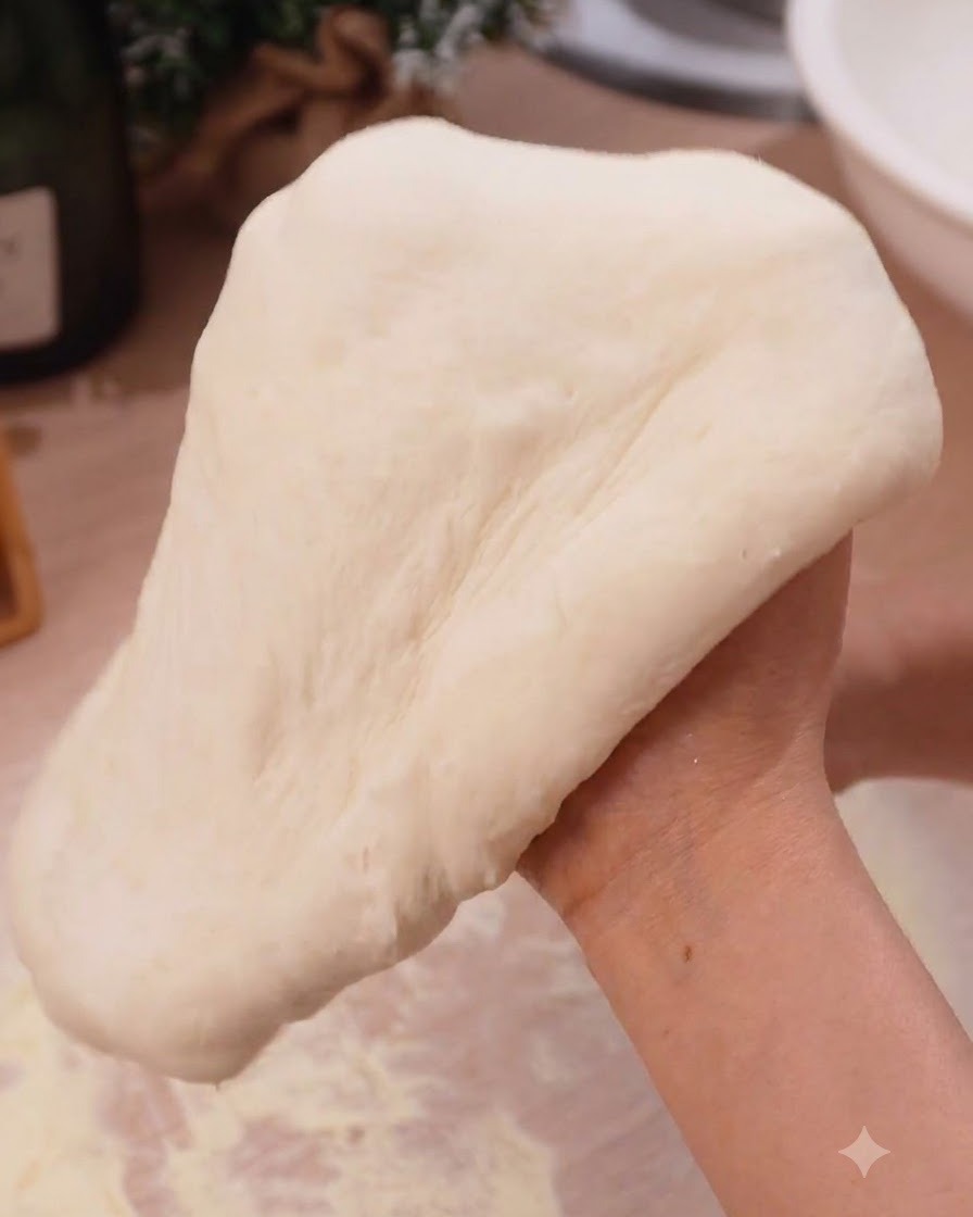 Impasto per pizza allungato morbidamente sopra le mani chiuse in un contesto di cucina.