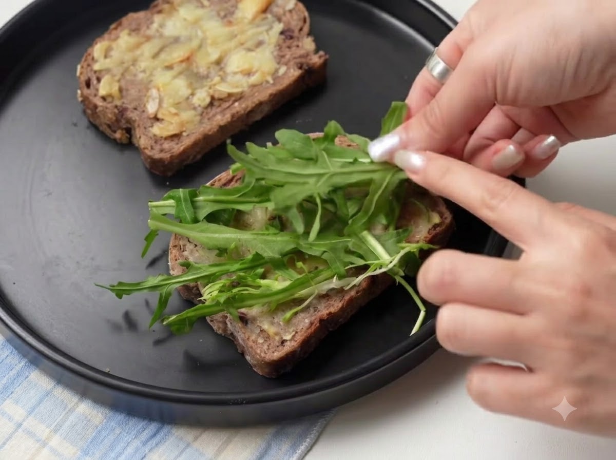 Foglie di rucola verde fresca disposte sopra le fette di pane stratificate con aglio arrosto.