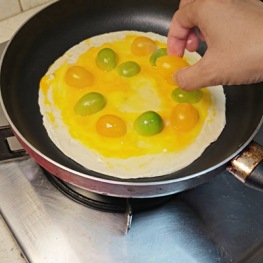 Pomodorini gialli e arancioni disposti a cerchio sullo strato di uovo che ricopre il pancake.