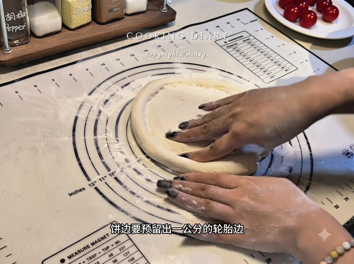 Mani che modellano i bordi di una base di pasta per pizza piatta su un tappetino in silicone per formare un bordo rialzato.