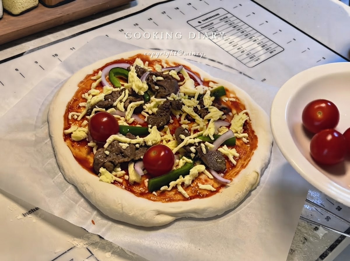 Una pizza completamente assemblata con formaggio, manzo, peperoni, cipolle e pomodorini interi su carta da forno.