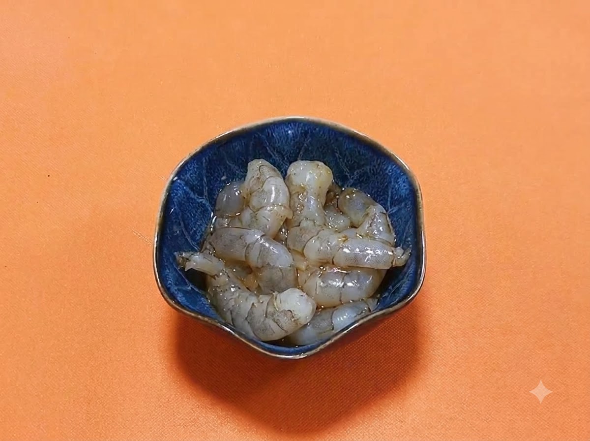Gamberi crudi pelati adagiati in una ciotola blu scuro con una marinata lucida di salsa di soia scura e spezie.