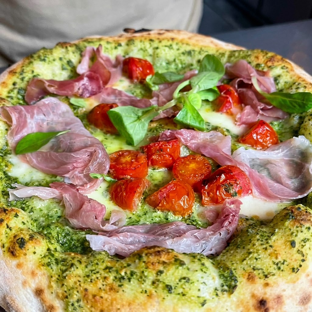 Erbe verdi fresche e noci tritate cosparse sopra una pizza.