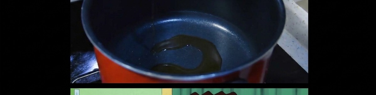 Un sottile strato di olio di sesamo che si scalda sul fondo di una pentola scura da cucina.