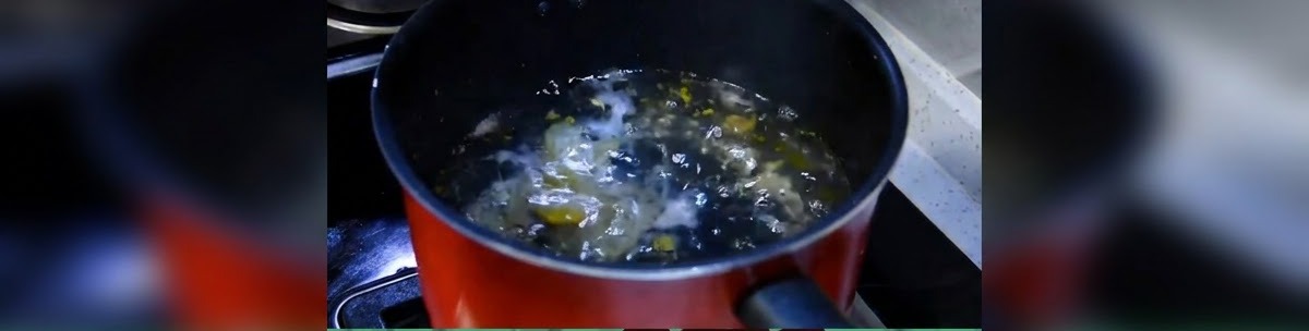 Una pentola scura da cucina con acqua che raggiunge un bollore leggero sul fuoco.