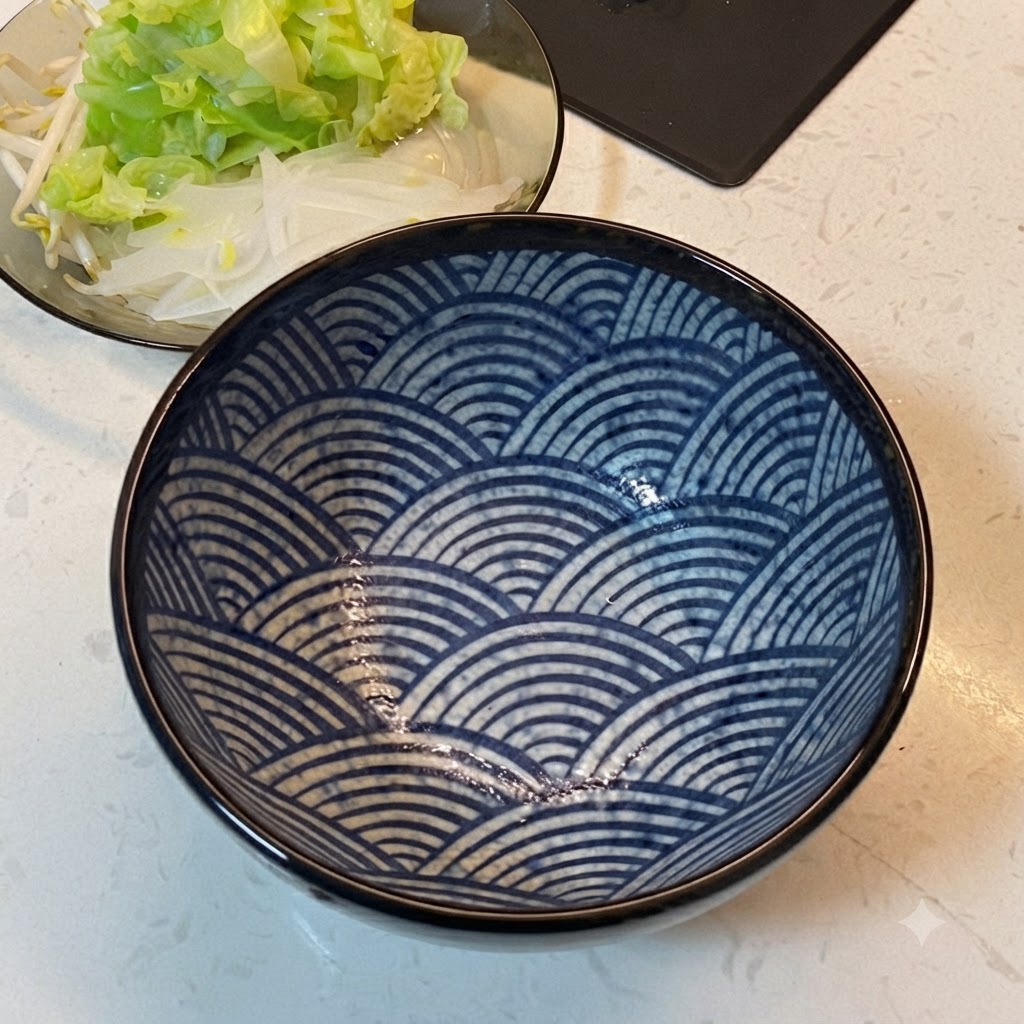Una ciotola da portata con fantasia blu accanto a un piatto di verdure disposte.