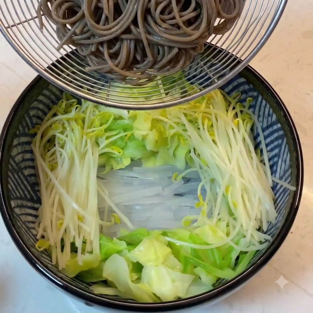 Noodles di grano saraceno cotti tenuti in un colino a rete sopra la ciotola con le verdure.