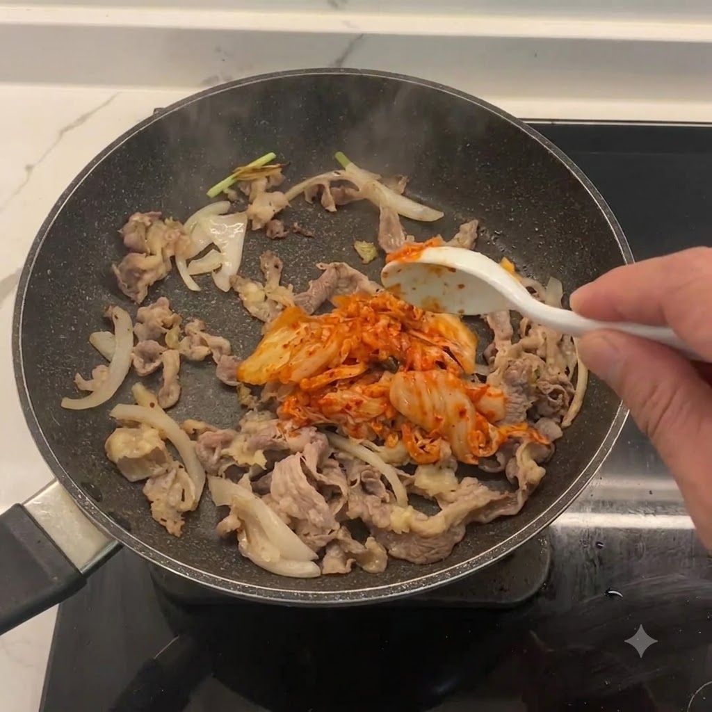 Kimchi tritato aggiunto e mescolato in padella con manzo e cipolle.