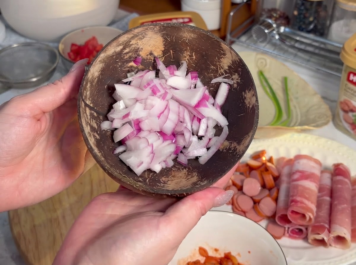Salsicce tagliate in piccole rondelle circolari disposte su un asse di legno accanto a carne arrotolata.