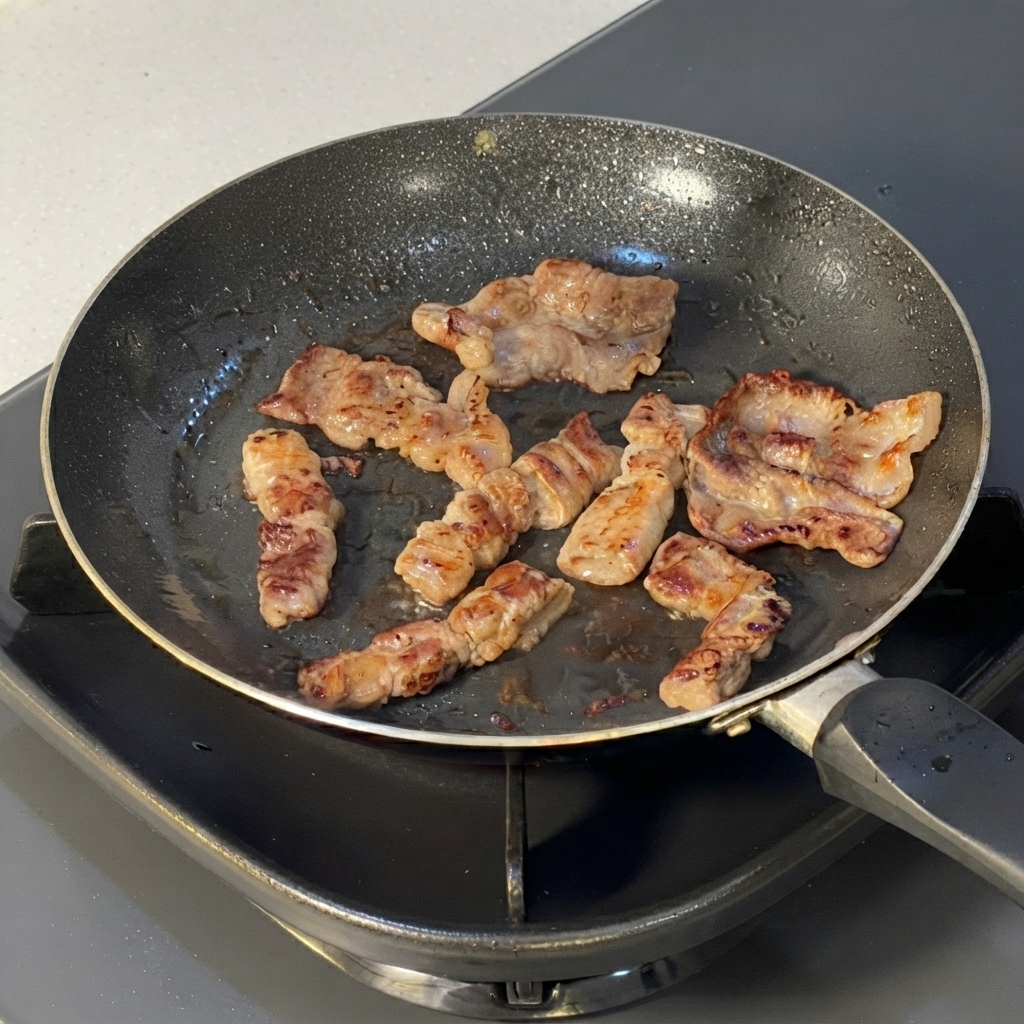Fettine di manzo cotte tagliate in segmenti più piccoli con le forbici da cucina allinterno di una padella.