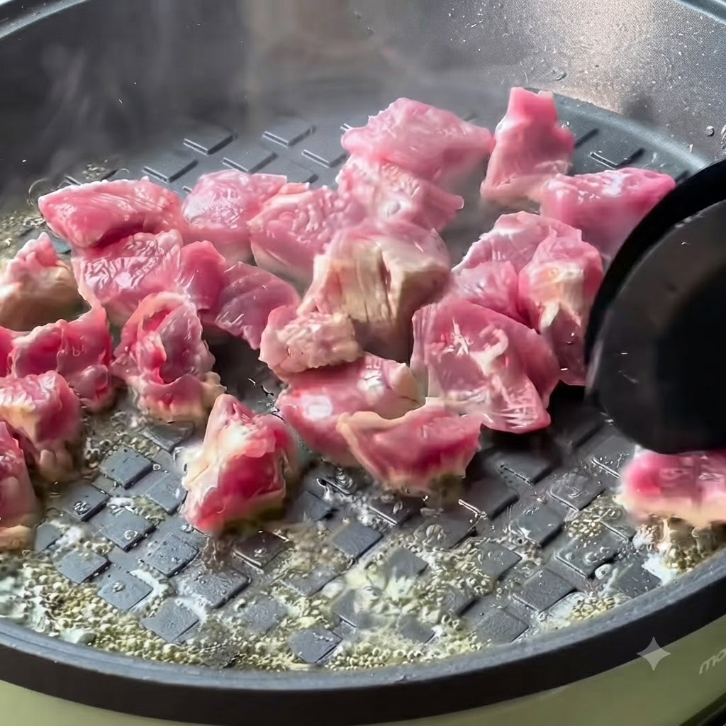 Cubetti di manzo in cottura che si dorano in una padella calda.