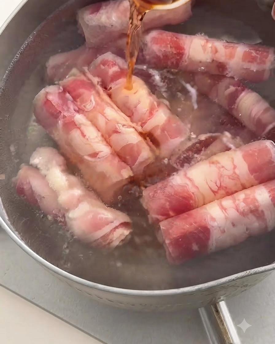 Vino da cucina scuro versato da un cucchiaio in una pentola di acqua bollente contenente involtini di manzo.