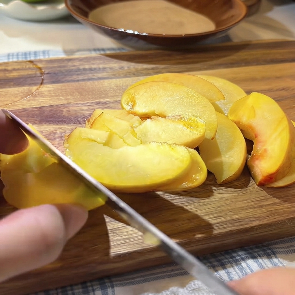 Semi e polpa di frutto della passione fresco versati con un cucchiaio sulle pesche gialle affettate sul tagliere.