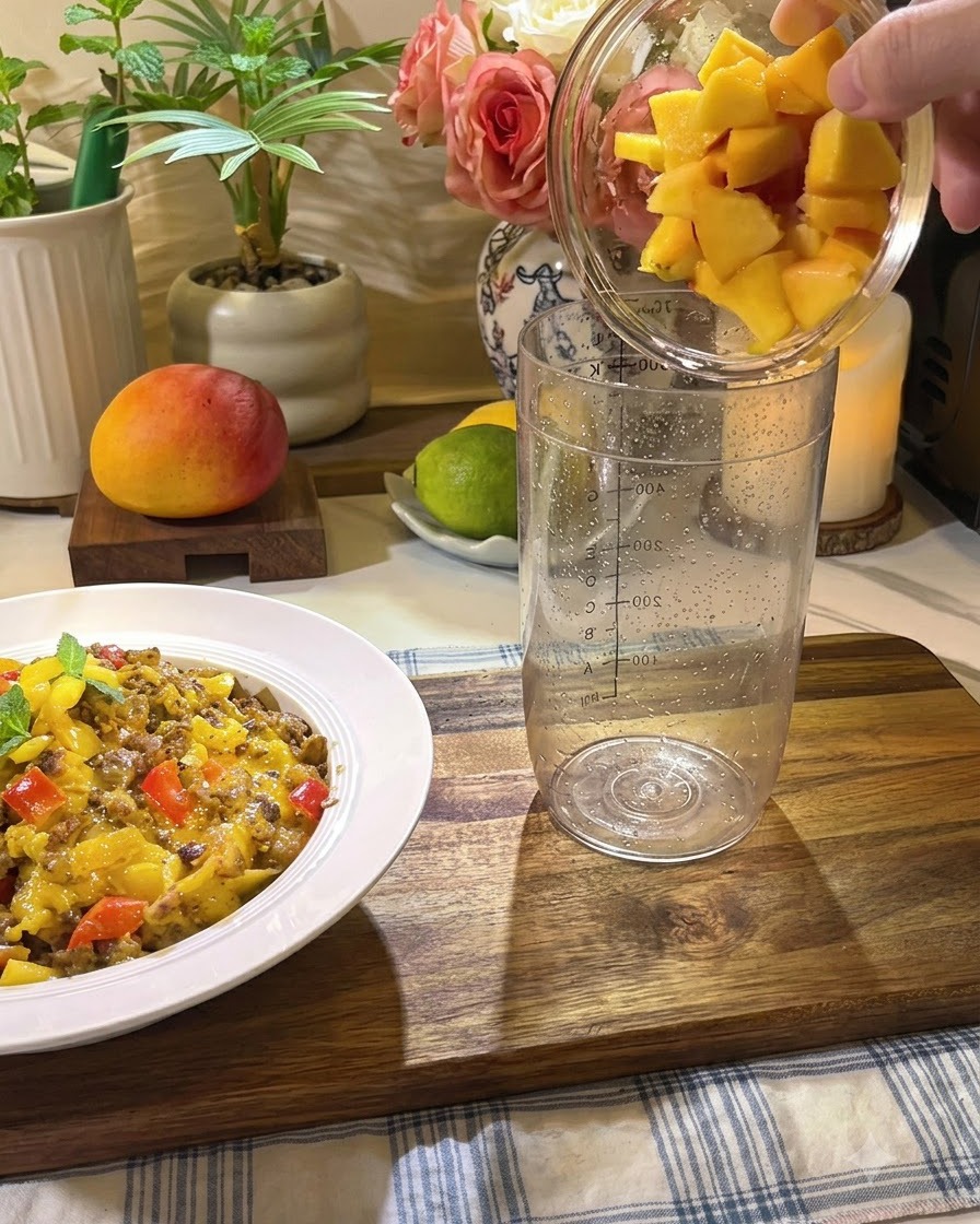 Pezzi di pesca fresca, miele e fette di limone versati in un bicchiere da cocktail alto e trasparente.