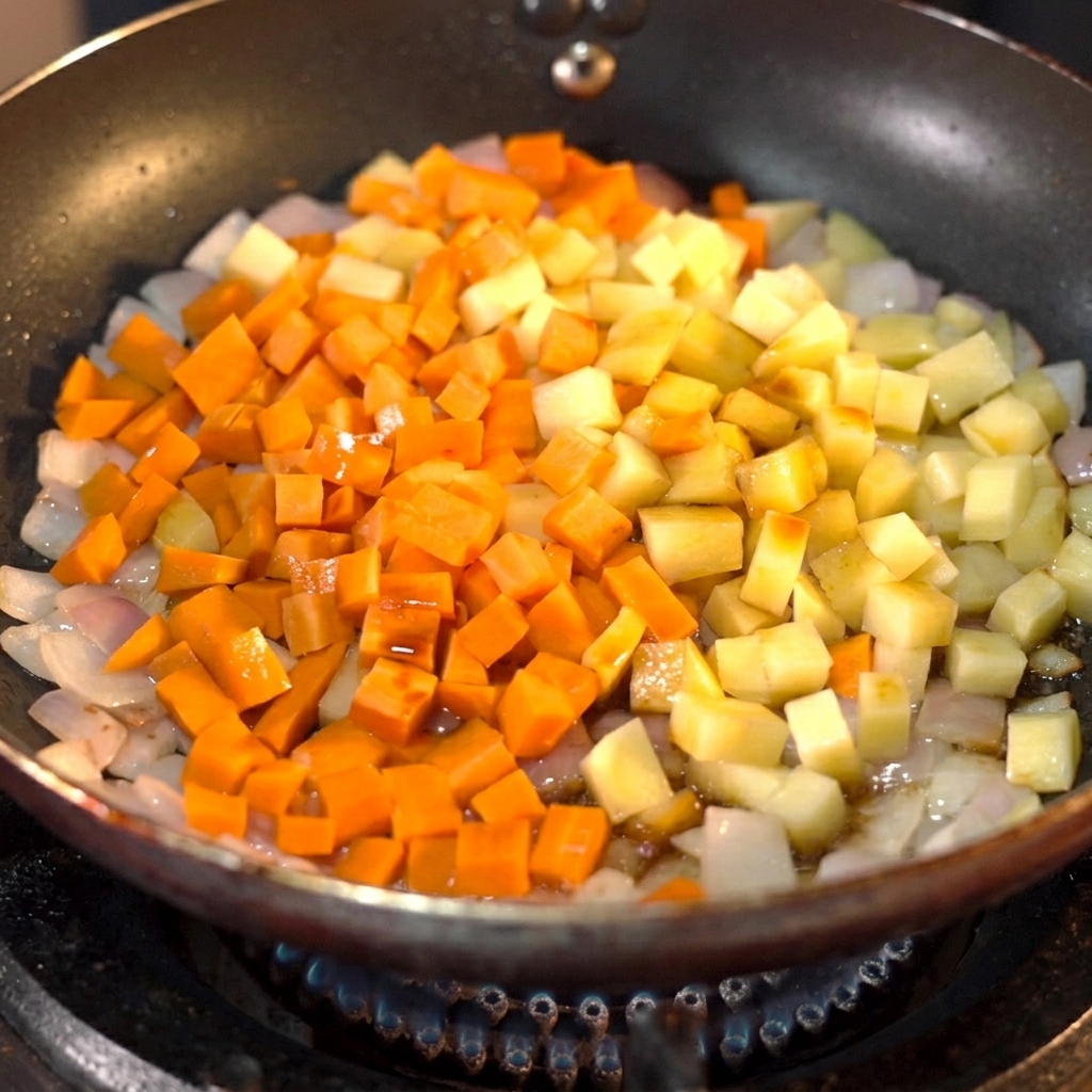 Salsa di soia scura versata su carote e patate a dadini in una padella.