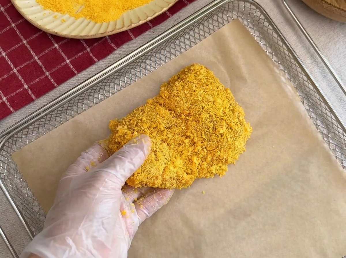 Una cotoletta impanata posizionata con cura su una griglia foderata con carta forno.