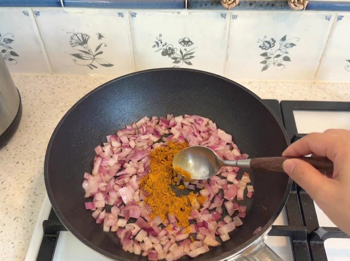 Curry in polvere dosato con un cucchiaio e aggiunto alle cipolle saltate in padella.