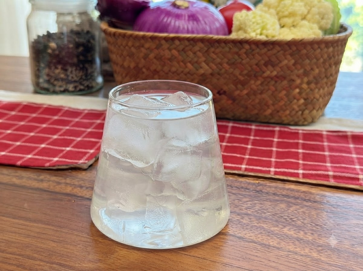 Acqua di cocco versata in un bicchiere trasparente pieno di cubetti di ghiaccio.