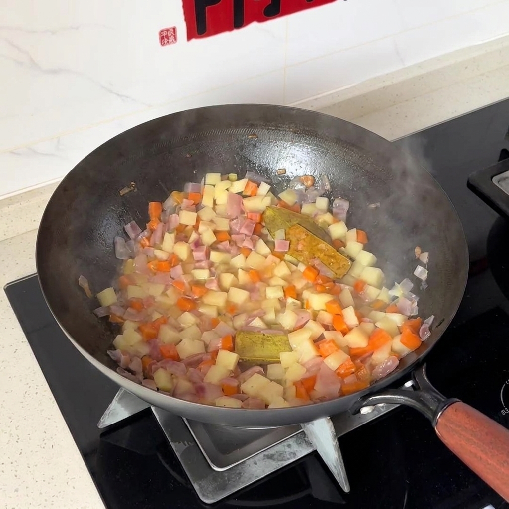 Patate e carote a dadini mescolate con le cipolle allinterno di un wok.