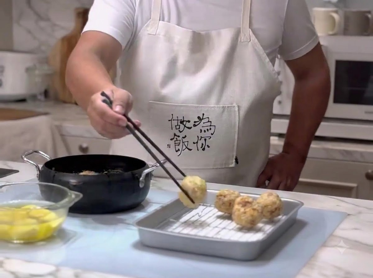 Polpette rimosse dallolio caldo usando le bacchette e posizionate su una griglia scolapiatti di metallo.