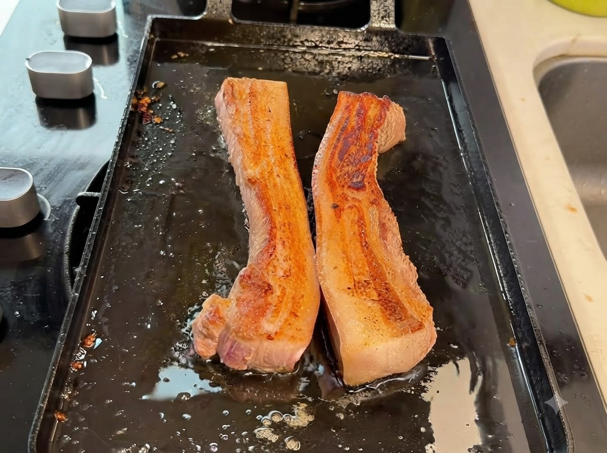 Strisce di pancia di maiale spesse tagliate a pezzi più piccoli con le forbici da cucina sulla piastra.