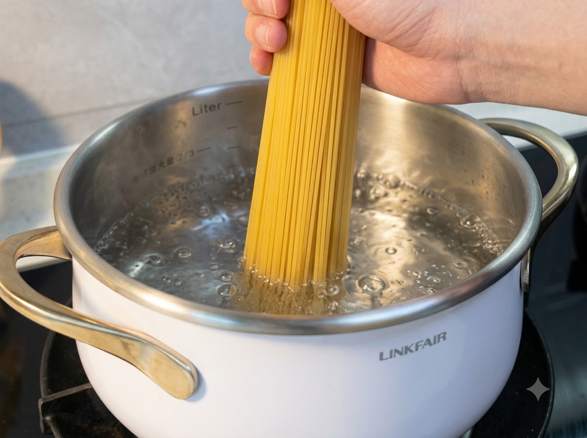 Una mano che tiene noodles di riso secchi mentre vengono immersi in una pentola di acqua bollente.