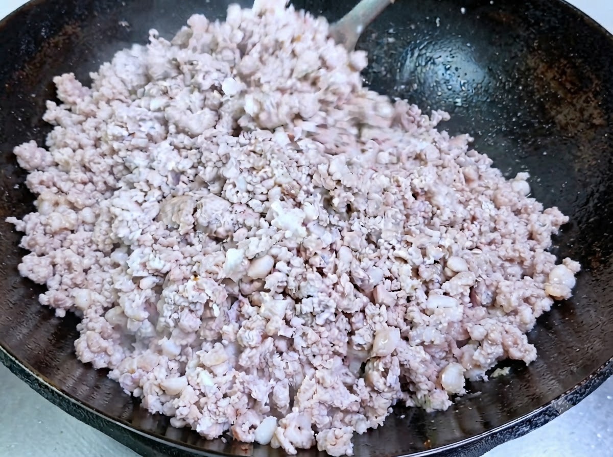 Carne di maiale macinata in cottura che diventa opaca allinterno del wok.
