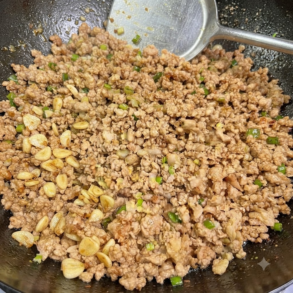 Carne macinata cotta mescolata con cipollotti e aglio saltata allinterno di un wok con luso di una spatola.