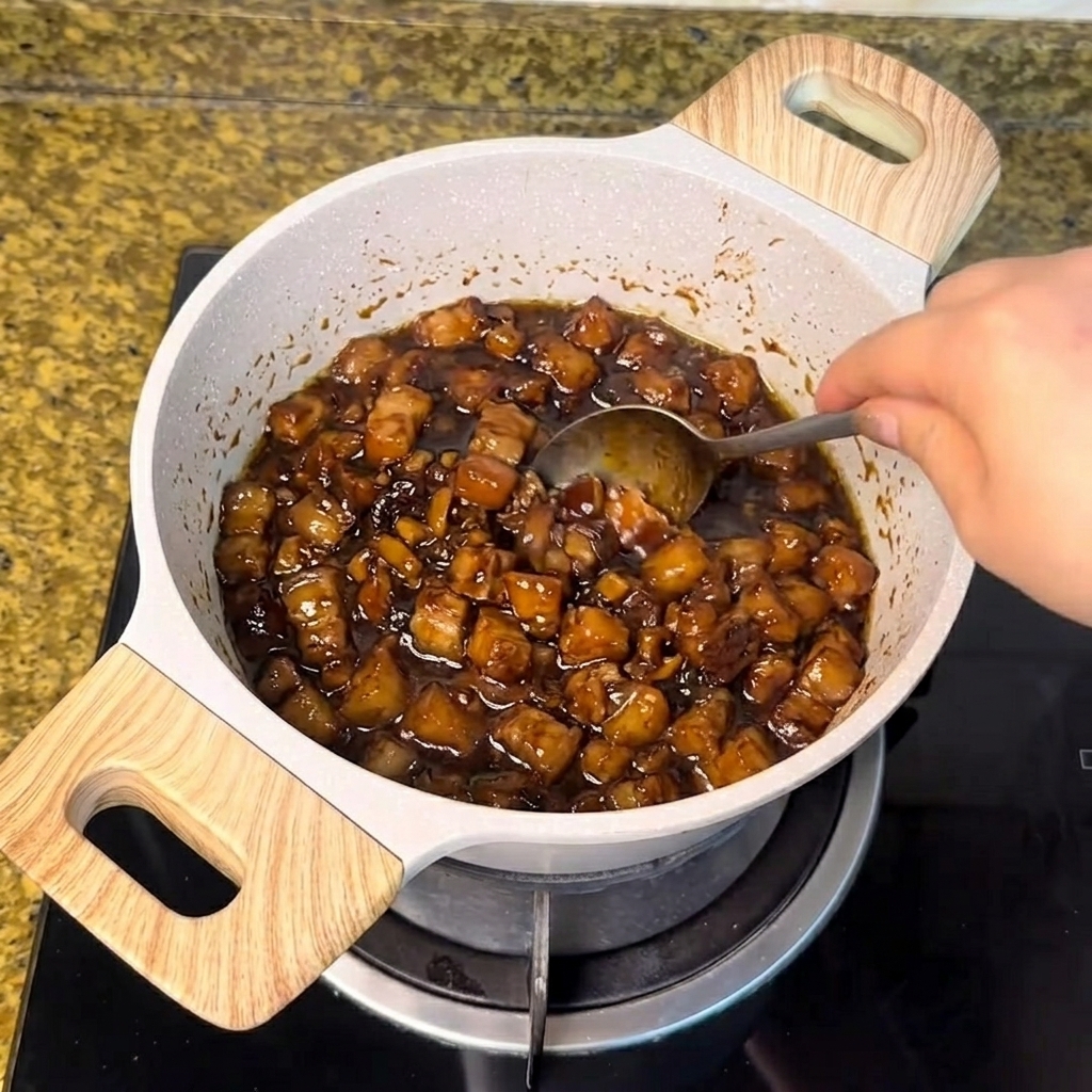 Zucchero bianco mescolato con un cucchiaio nella salsa di carne scura in ebollizione.