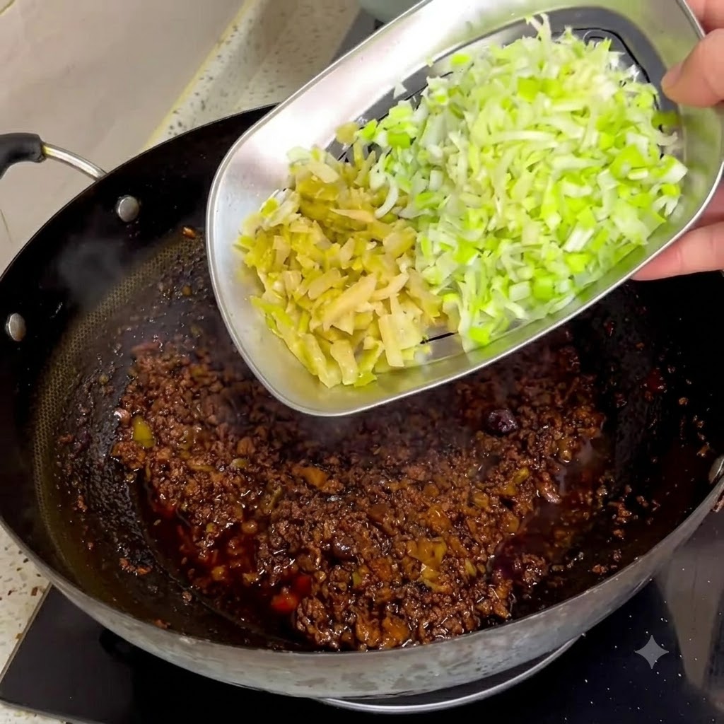 Senape conservata tritata e cipollotti fatti scivolare da un vassoio di metallo in una salsa di carne scura in un wok.