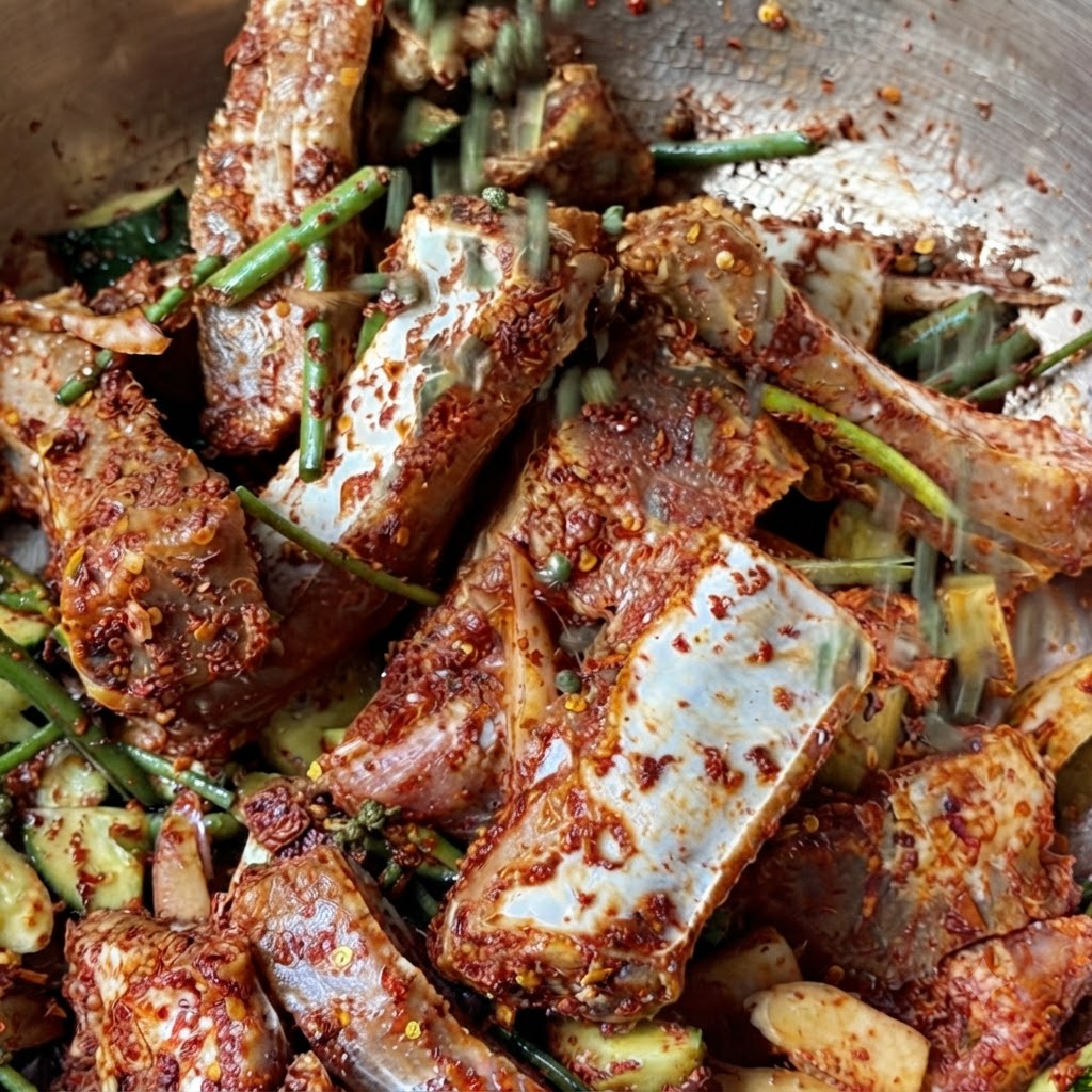 Una manciata di grani di pepe verde del Sichuan interi che cadono sulle costine di maiale marinate.