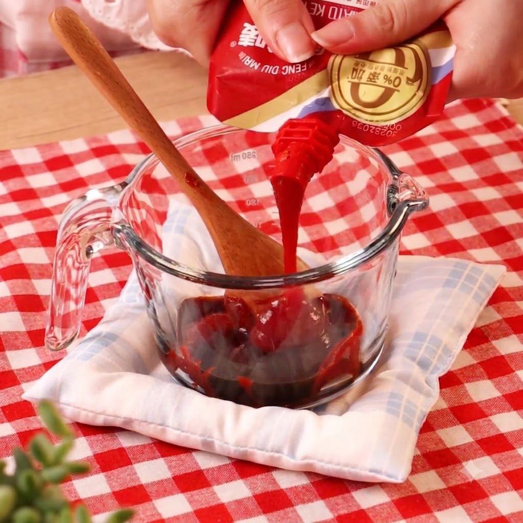 Pasta di peperoncino versata da una bustina in un misurino di vetro contenente altri liquidi.