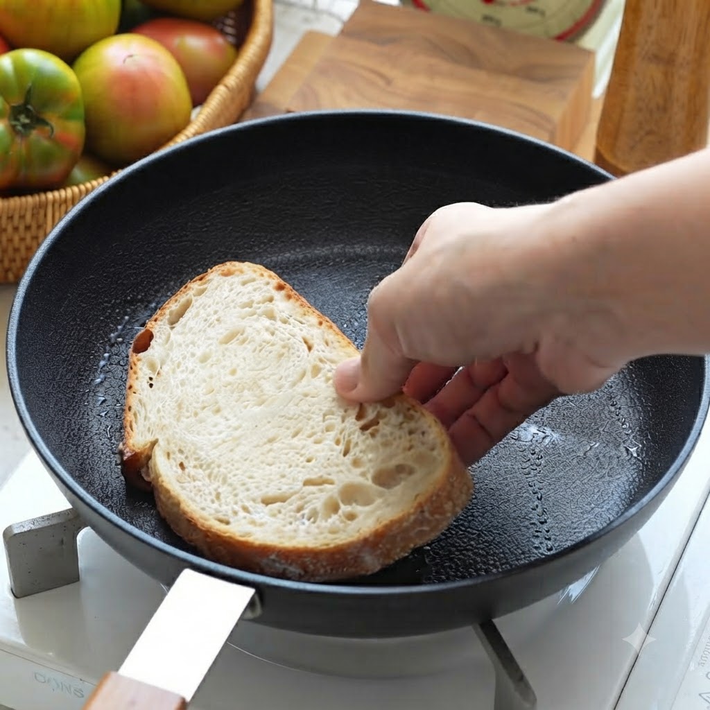 Una fetta di pane a lievito madre posizionata in una padella nera per essere tostata.
