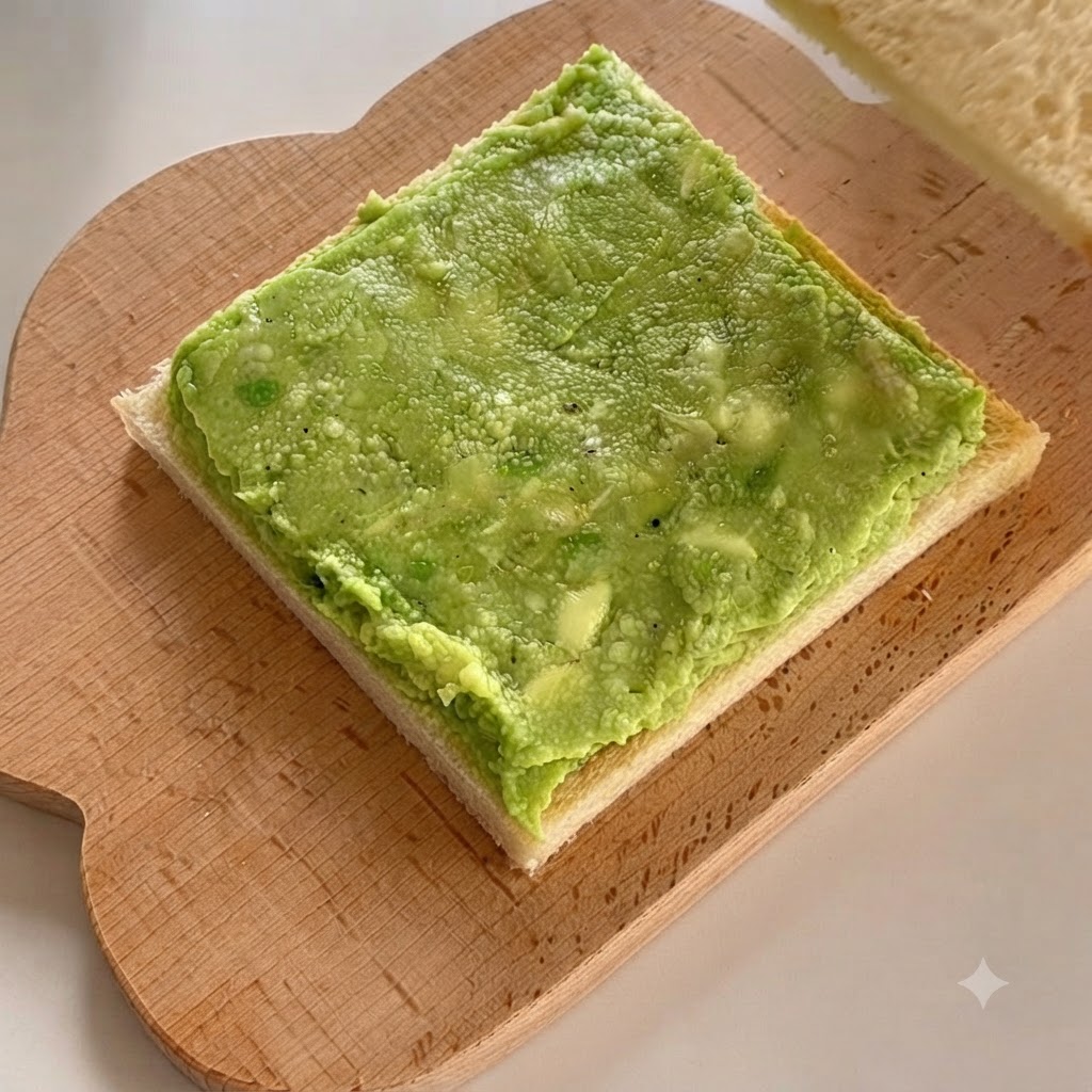 Una seconda fetta di pane bianco posizionata direttamente sopra la pasta di avocado a strati.