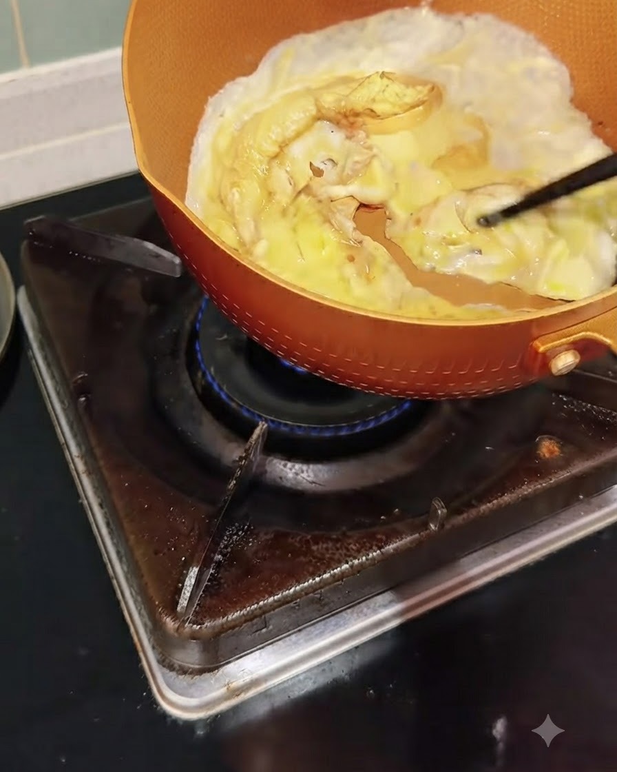 Uova in cottura in una padella che vengono spinte e strapazzate delicatamente con le bacchette.