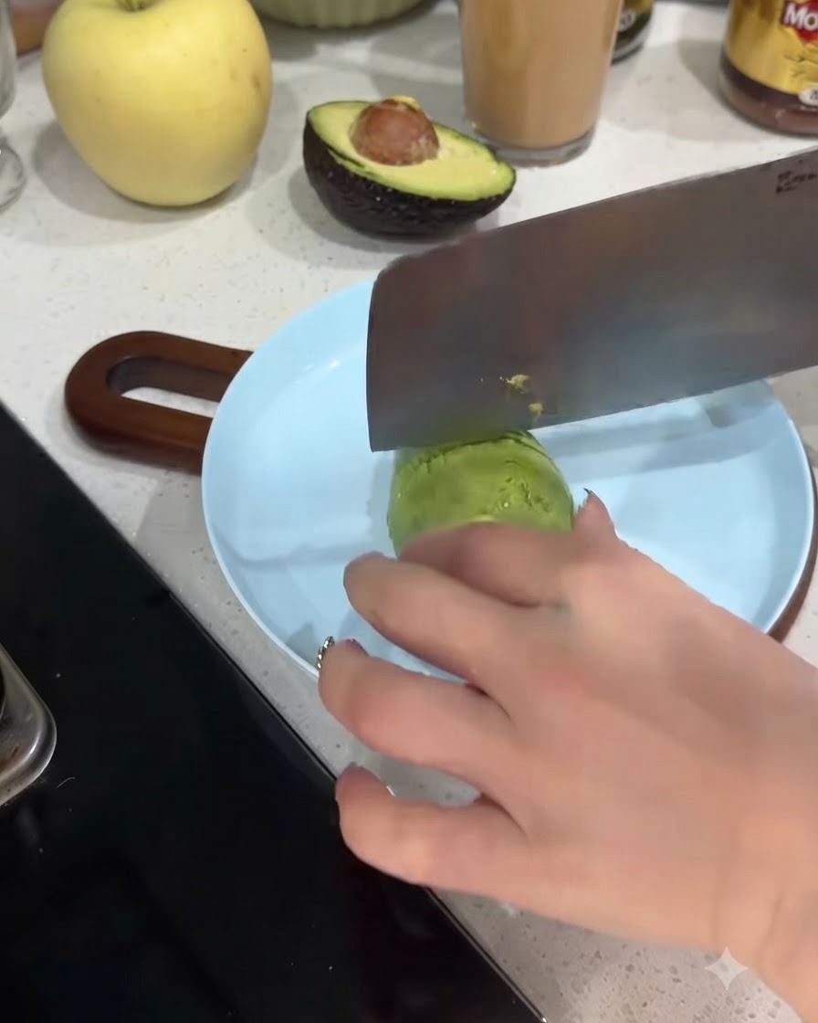 Una metà di avocado tagliata a fette sottili su un piatto azzurro.