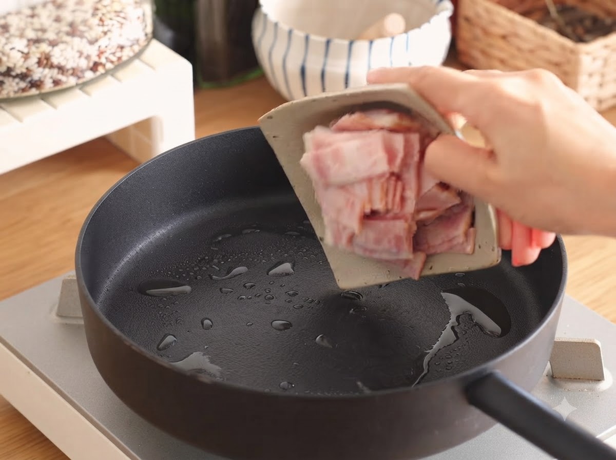 Strisce di pancetta che sfrigolano in una padella con una piccola quantità di olio.