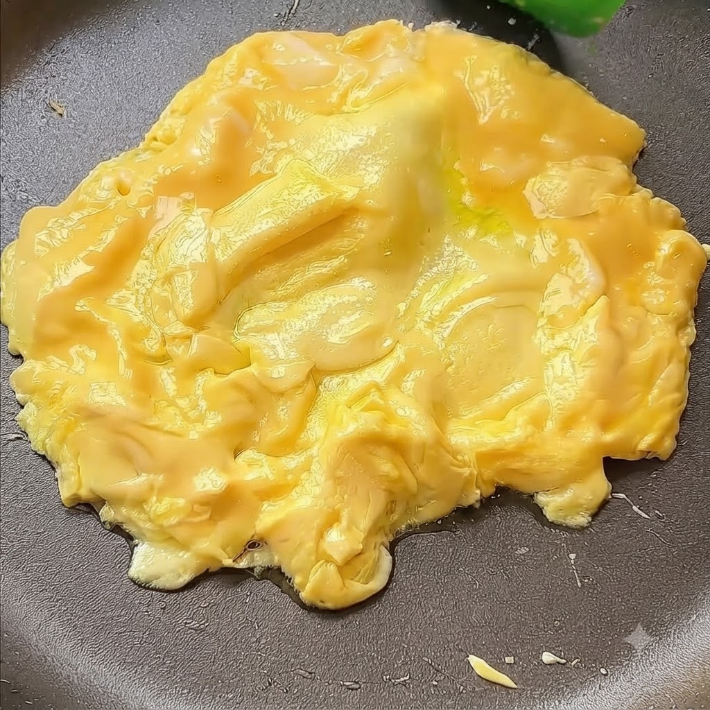 Uova spinte verso il centro di una padella con una spatola.