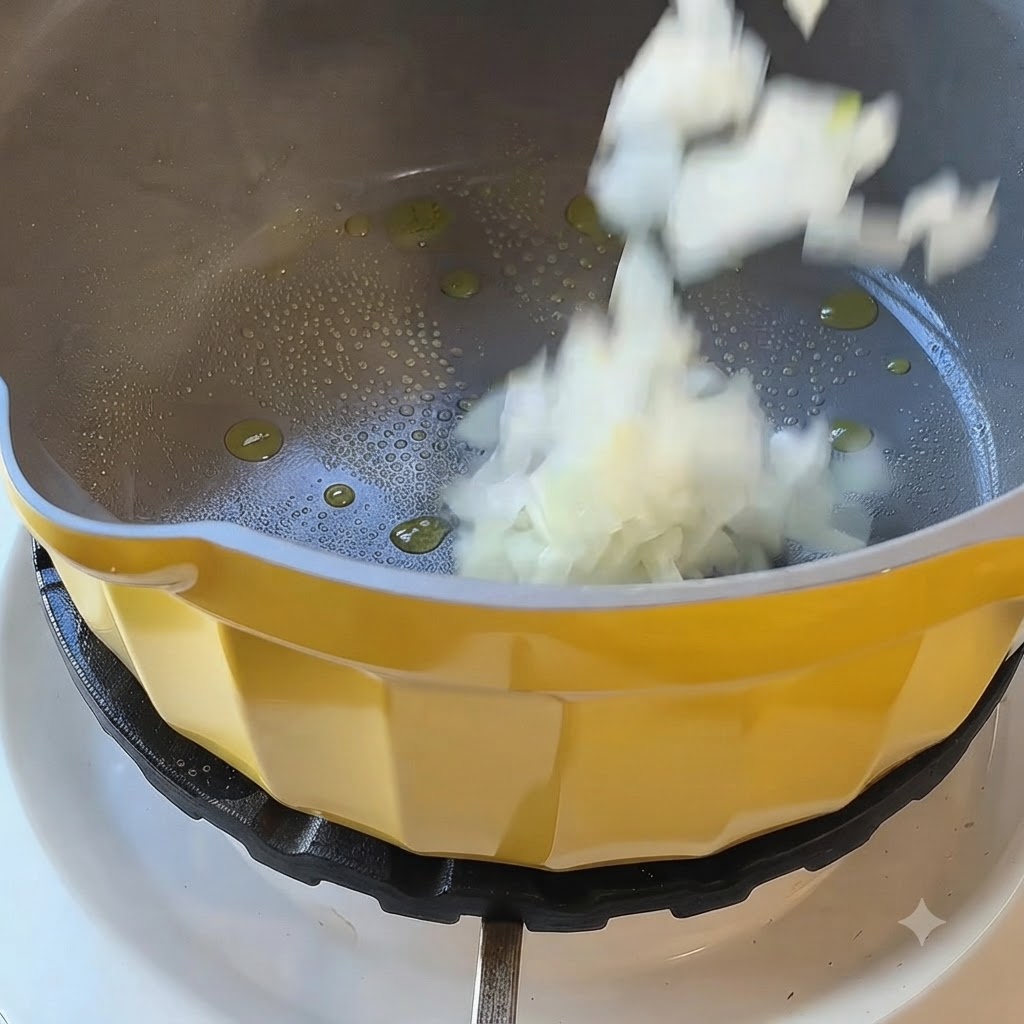 Cipolle bianche tritate che cadono in una pentola gialla con olio caldo su un fornello.