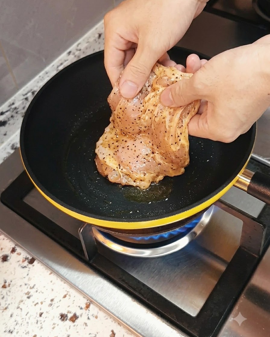 Petto di pollo marinato inserito in una padella calda con una fiamma a gas sottostante.