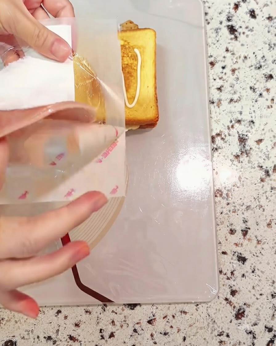 Una fetta di prosciutto posizionata sopra i componenti del pane del panino in assemblaggio.