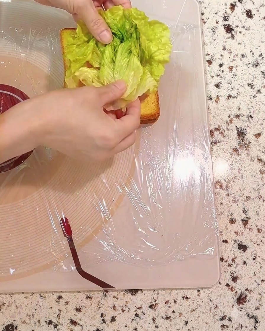 Foglie di insalata verde fresca posizionate sugli strati del panino.
