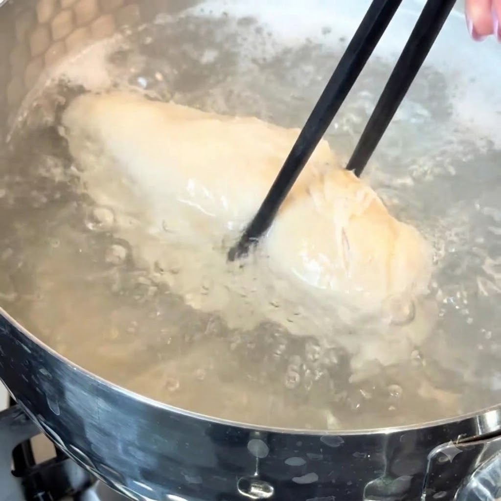 Un petto di pollo che sobbolle in acqua calda dentro una pentola.