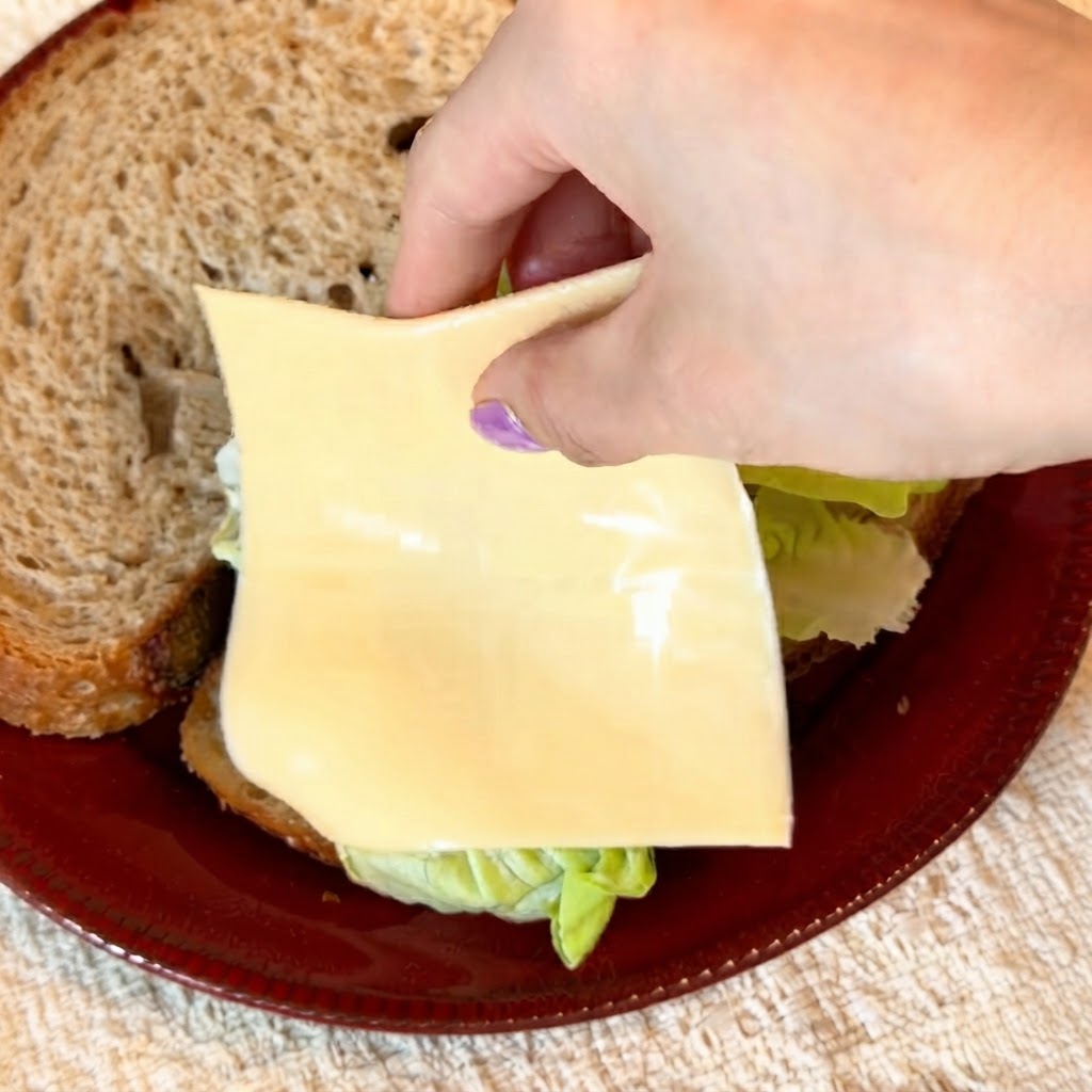 Due fette di formaggio giallo a ridotto contenuto di grassi sistemate con cura sullinsalata verde.
