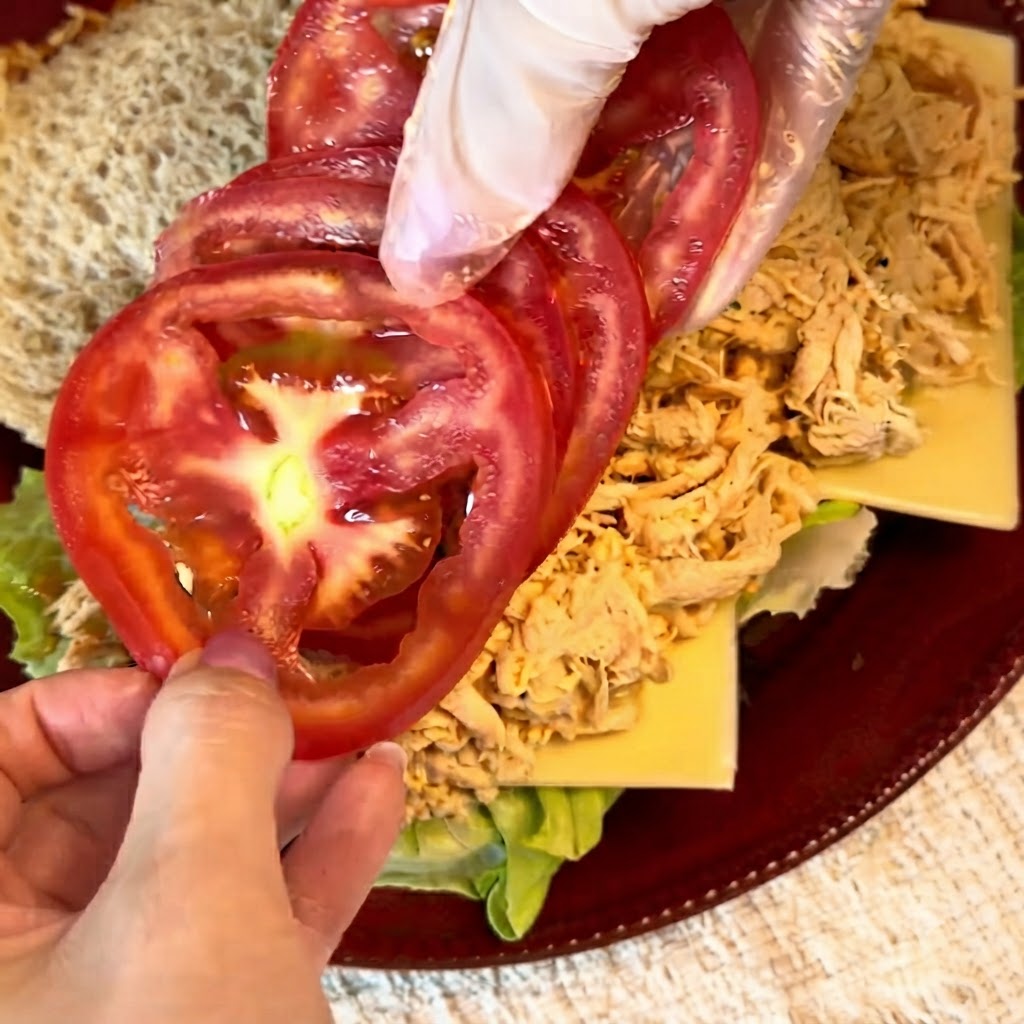 Fette di pomodoro rosso fresco sistemate ordinatamente sopra il ripieno di pollo sfilacciato.
