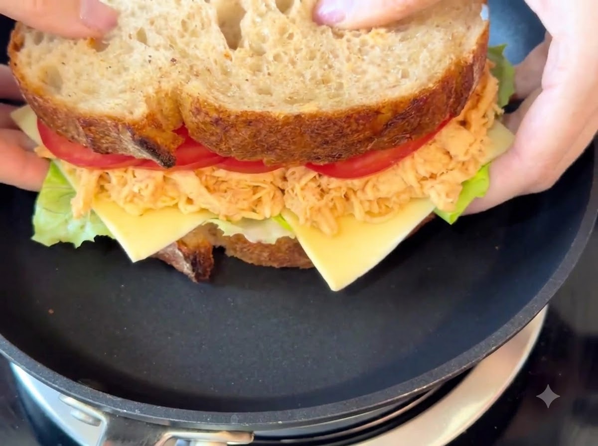 Il panino completo in cottura dentro una padella nera a fuoco basso.